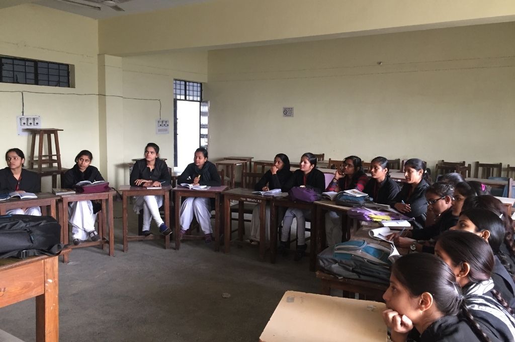 Girls in a classroom, listening to a lecture. A nonprofit learns the importance of strategy and communication when planning for scale.