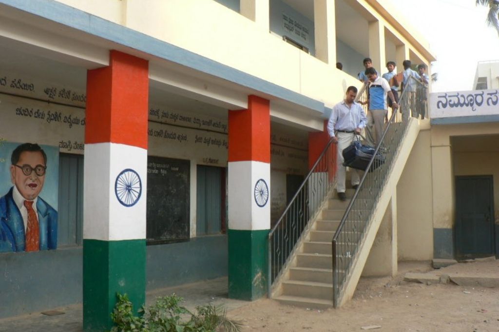 People climbing down a flight of stairs of a building with a mural of Babasaheb Ambedkar--constitutional values