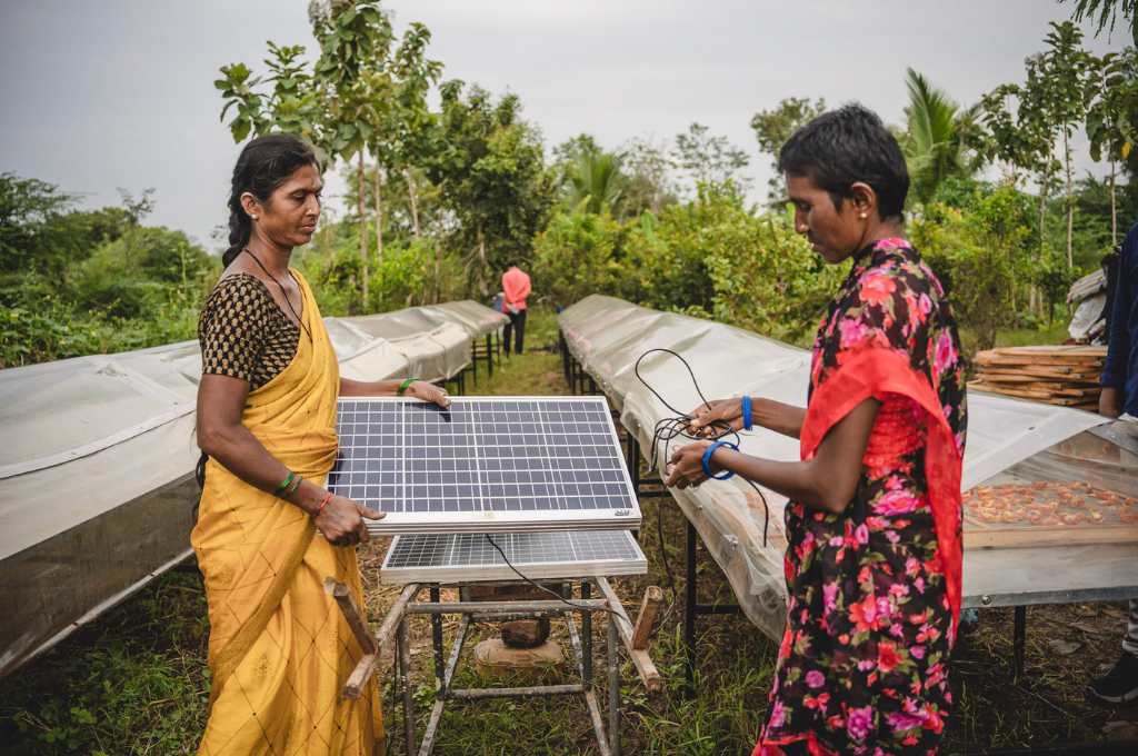 two women looking at a solar panel-renewable energy