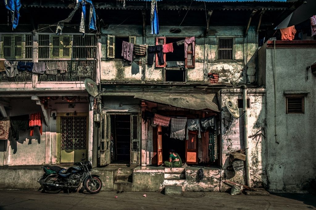 A photo a house in Vasad, Gujarat with a women sitting in the verandah-poverty